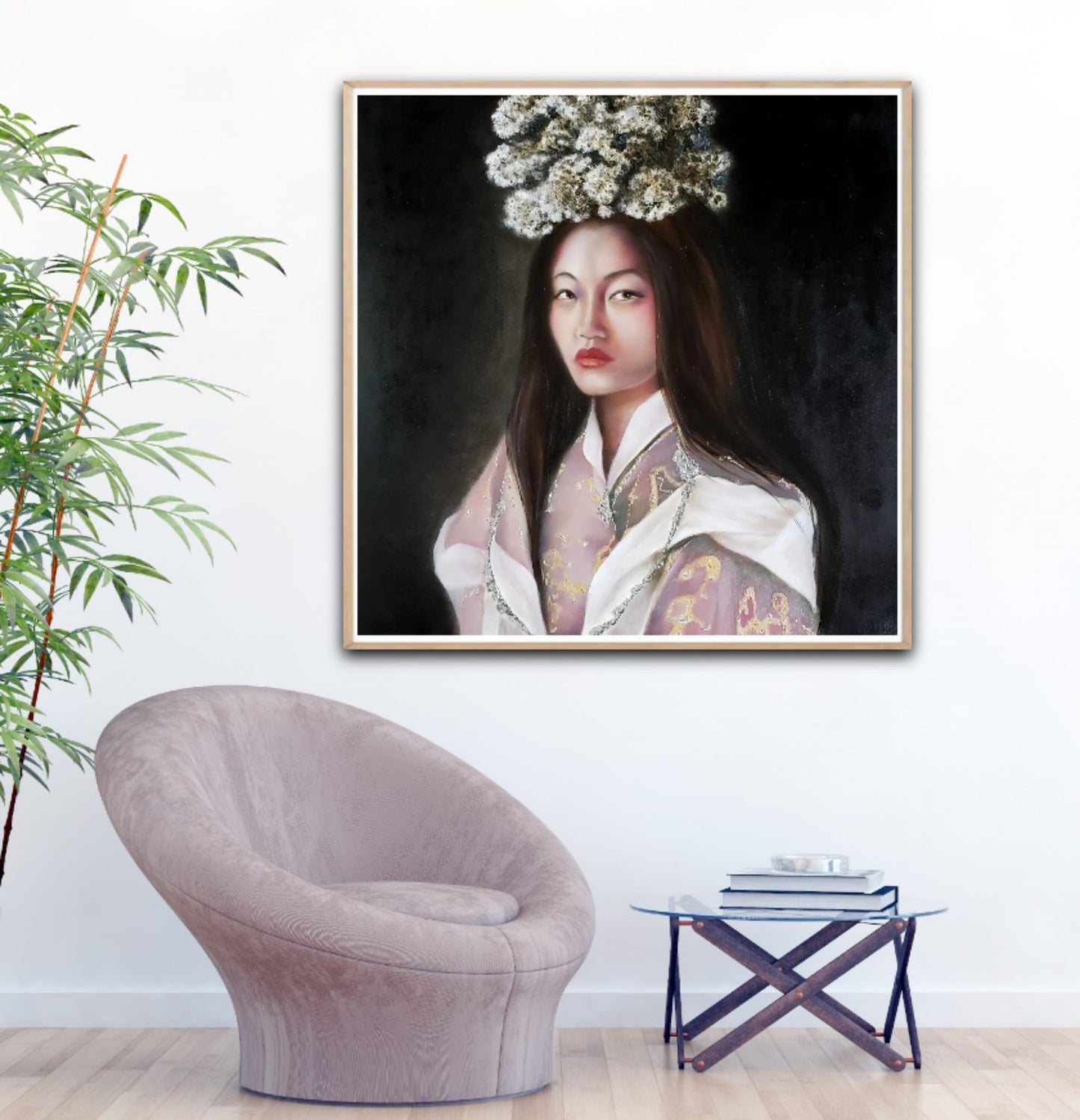 A square 24x24 original photorealistic oil portrait titled Woman from Bhutan by Nersel Muehlen in a light wood frame. It is displayed in a modern minimalist interior above a mauve lounge chair and a glass side table with a green bamboo plant on Mitsooz.
