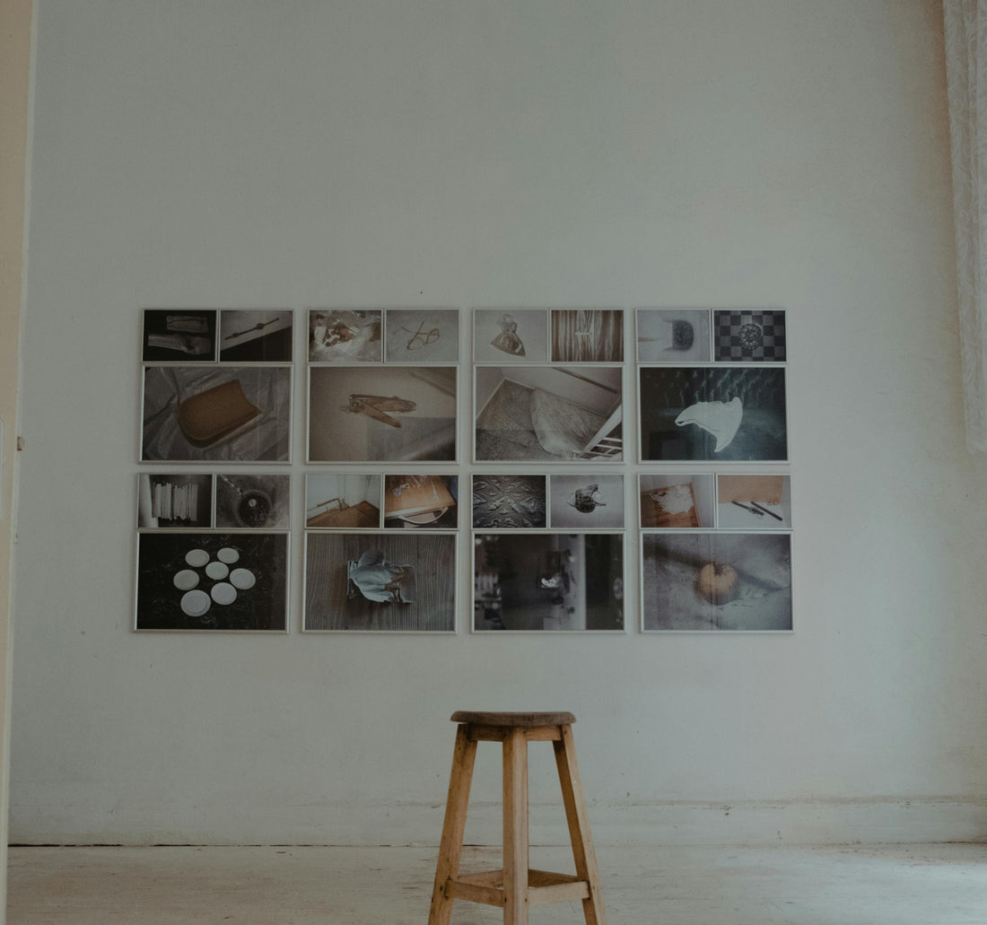Minimalist home interior with a curated grid of photography prints and a wooden stool, representing the intentional home philosophy at Mitsooz.