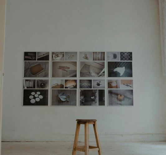 Minimalist home interior with a curated grid of photography prints and a wooden stool, representing the intentional home philosophy at Mitsooz.