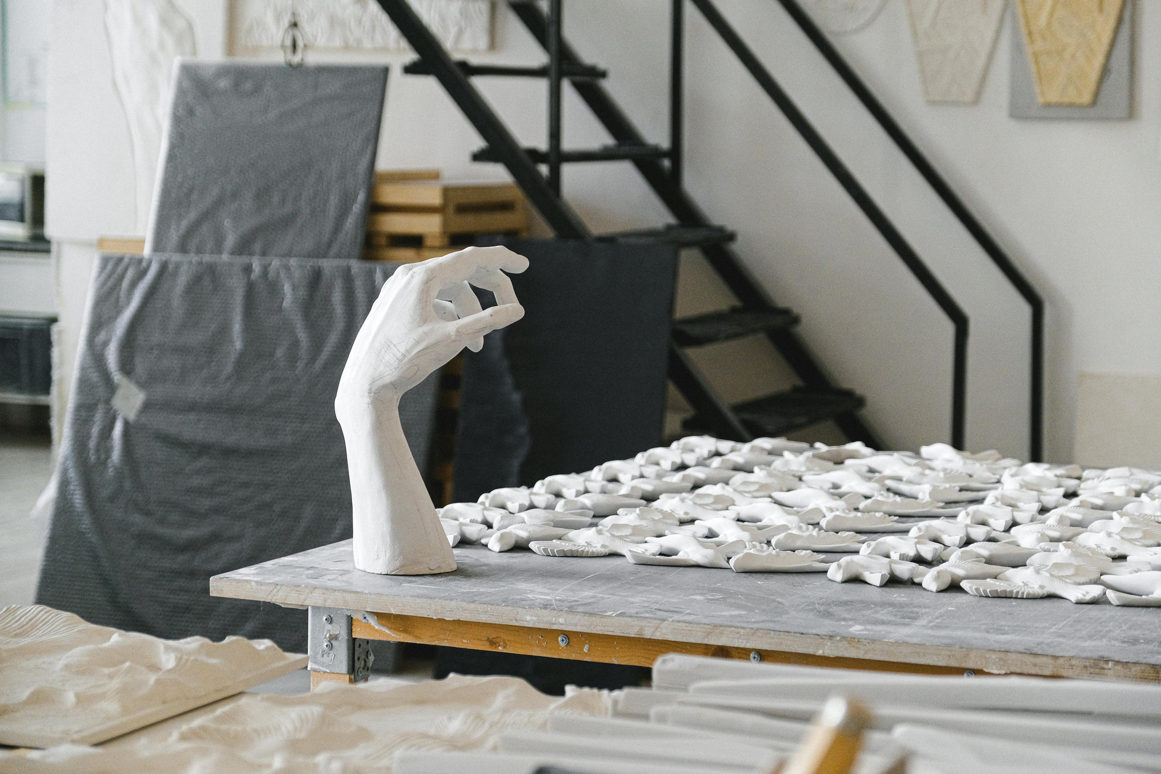 Minimalist white plaster hand sculpture in an artist studio representing the supportive and intentional communication at Mitsooz.