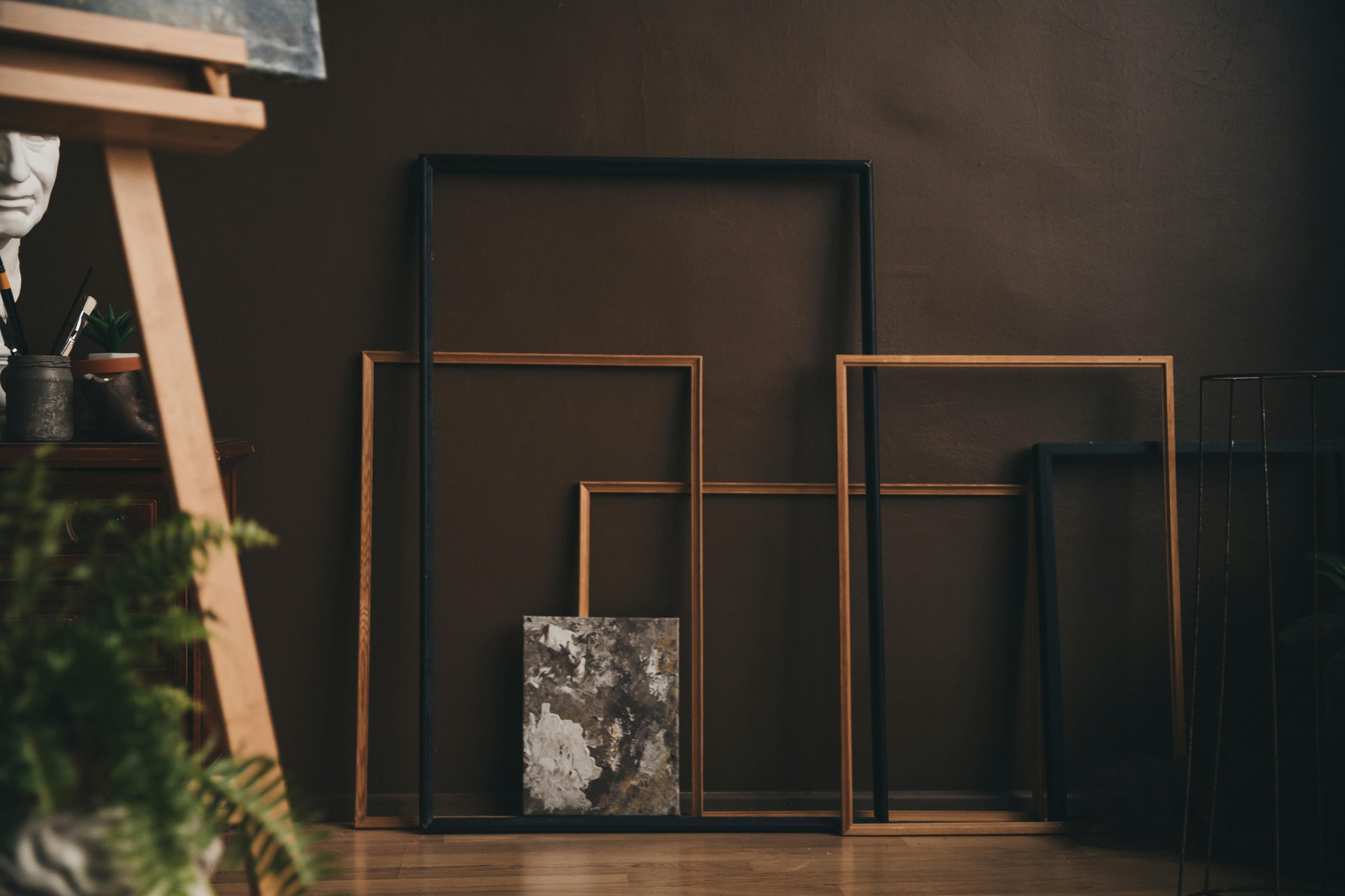 A curated collection of archival frames leaning against a dark studio wall: establishing the foundation for the Mitsooz Archive and the integration of vision and form.