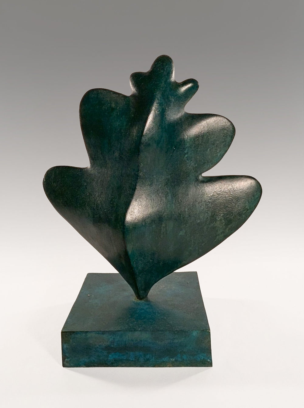 A vertical bronze sculpture titled Common Hawthorne Leaf by Andree Brown featuring a hand-formed organic leaf with a rich verdigris green studio patina on a square bronze base on Mitsooz.