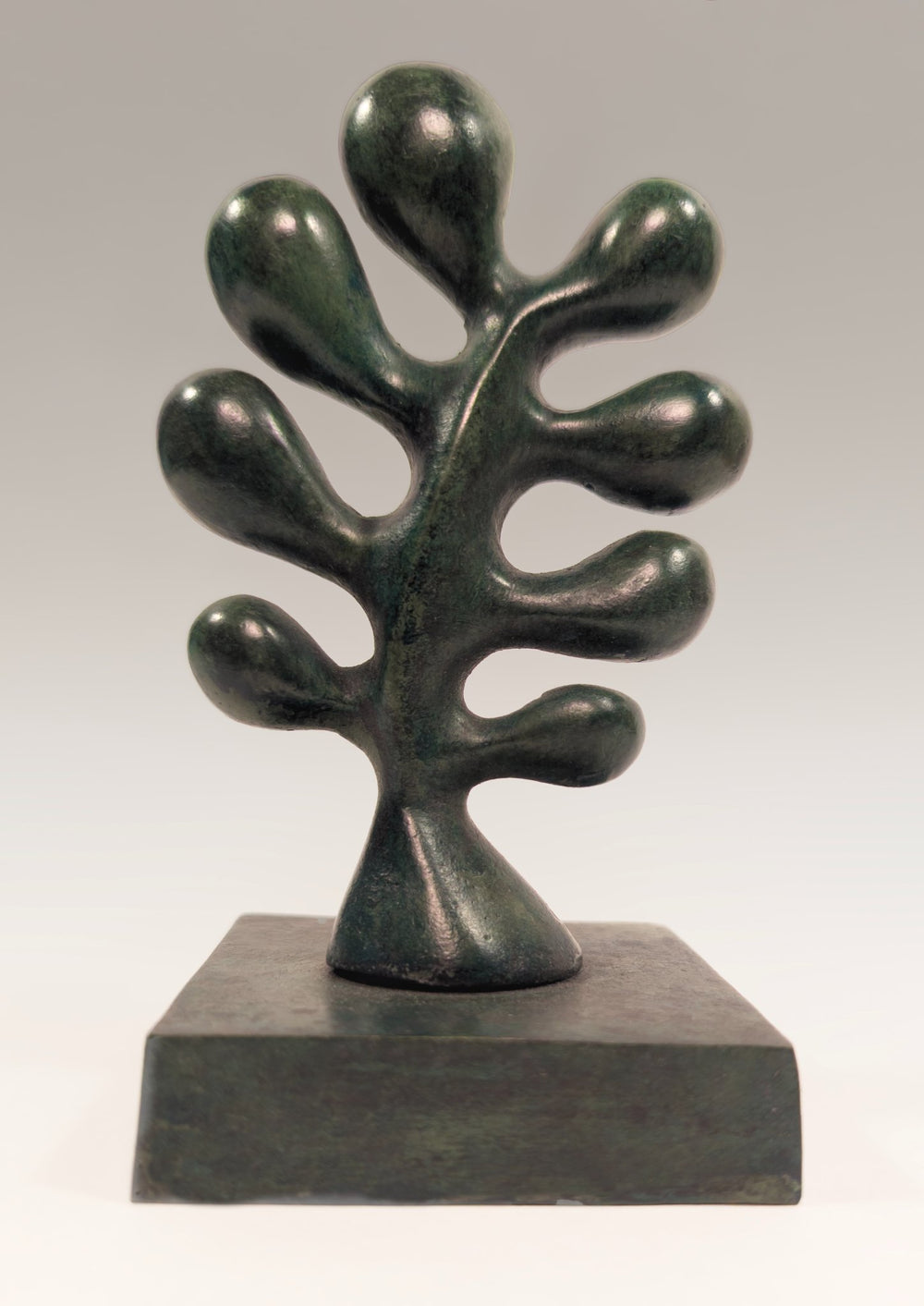 A vertical dimensional porcelain sculpture titled Common Oak Leaf by Andree Brown featuring a hand-formed mottled green leaf on a thin black metal stand on Mitsooz.