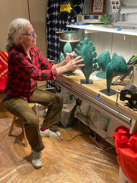 Mitsooz Artist Andree Brown working at her studio bench with several hand-formed sculptural Works. The image highlights the sustained attention and material transformation involved in her iterative creative process.