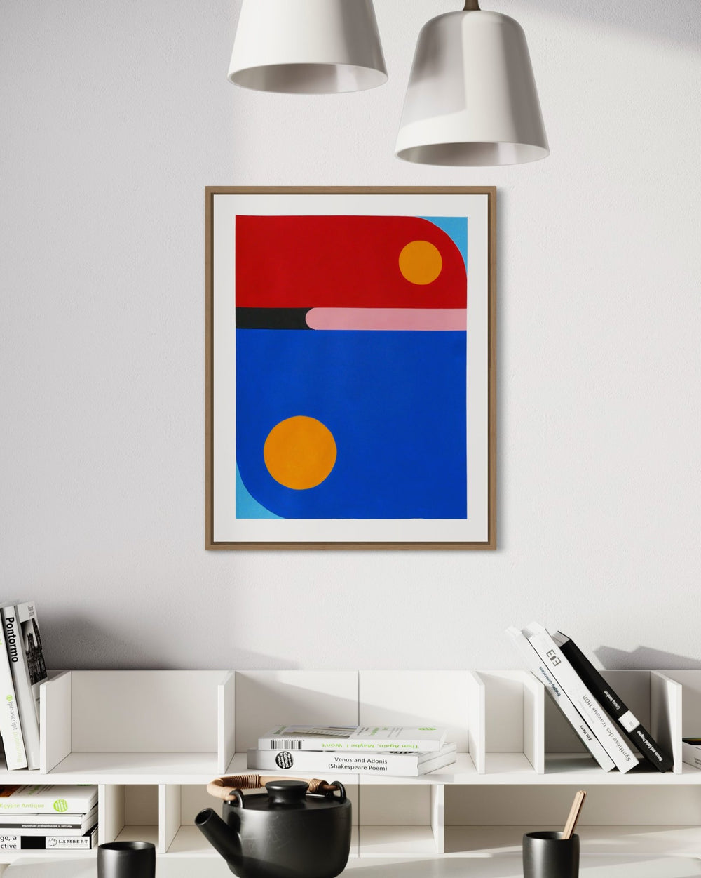 A vertical original abstract painting titled Day Train by Holly McWhorter, featuring bold fields of primary red and blue with sun-like yellow circles. The acrylic gouache work is displayed in a framed presentation on a white wall above a modern bookshelf with a black teapot on Mitsooz.