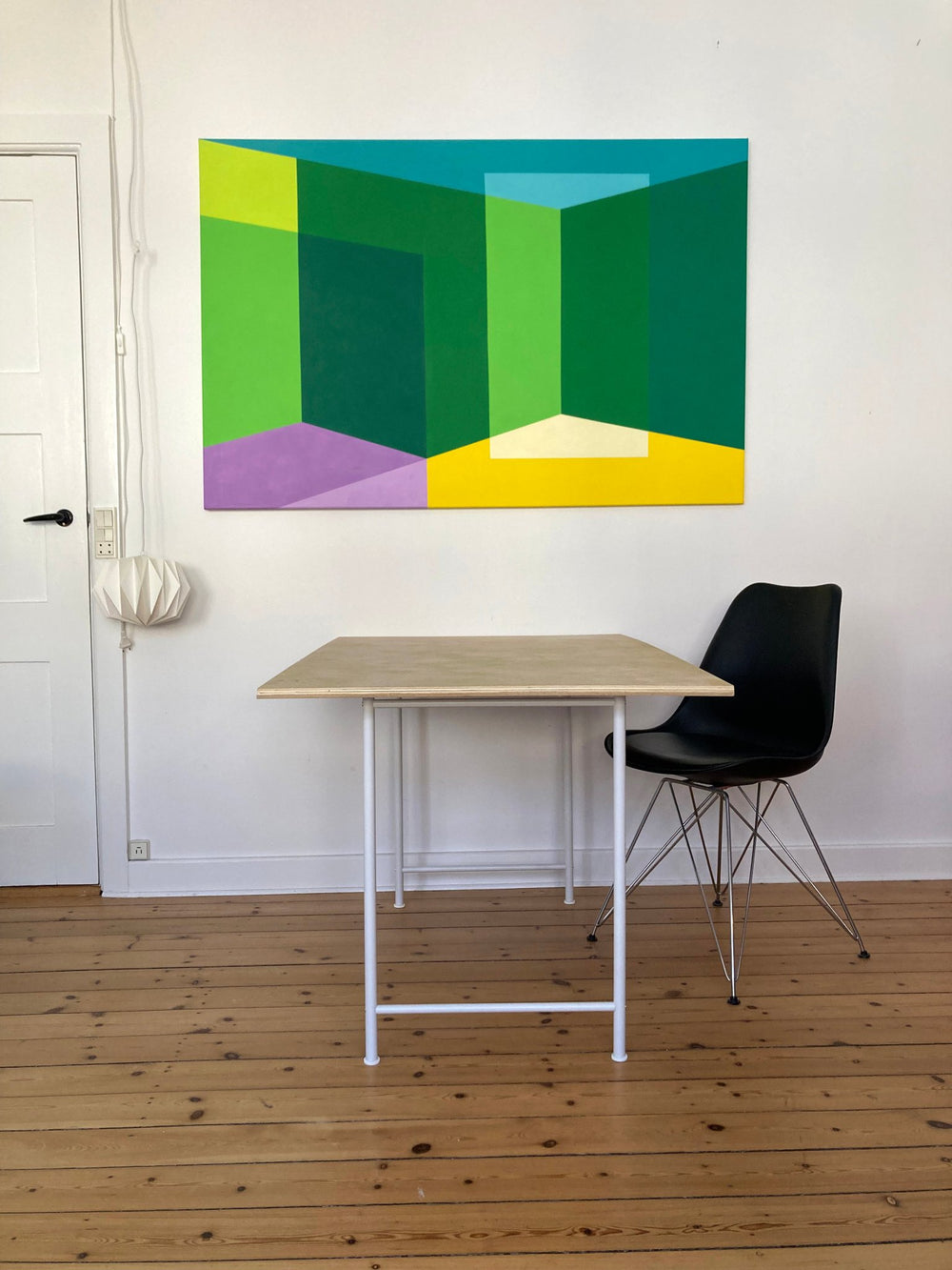 A large horizontal original abstract painting titled Space and Light by Holly McWhorter, featuring overlapping hard-edge fields of green, yellow, and lavender. The work is displayed in a modern Copenhagen interior above a minimalist light wood desk on Mitsooz.