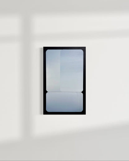 A vertical 15x24 original atmospheric abstract painting titled Stacked by Kevin Cross, featuring overlapping silver and blue gradients on foam backed canvas. The work is displayed on a clean white wall with soft diagonal window shadows in a contemporary minimalist interior on Mitsooz.