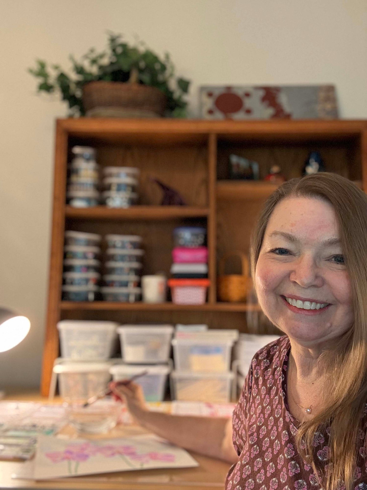 Ruth working on a floral watercolor painting at her studio desk, a featured artist on Mitsooz.