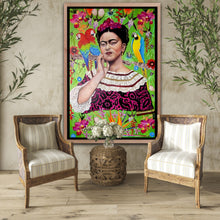 A monumental 40x60 original photorealistic oil portrait titled Frida Kahlo by Nersel Muehlen, featuring a vibrant botanical tapestry with parrots and exotic flowers. The painting is displayed in a bright, coastal-inspired living space between two rattan armchairs and a woven wicker side table on Mitsooz.
