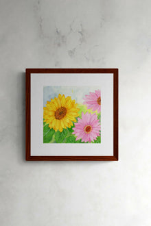 Square original botanical watercolor titled Pink and Yellow Gerbera Daisy by Ruth Wall featuring sunlit blooms in a mahogany frame on Arches paper at Mitsooz.
