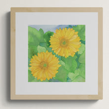 A square original botanical watercolor titled Two Yellow Gerbera Daisies by Ruth Wall featuring vibrant golden blooms in a light natural wood gallery frame on Mitsooz.